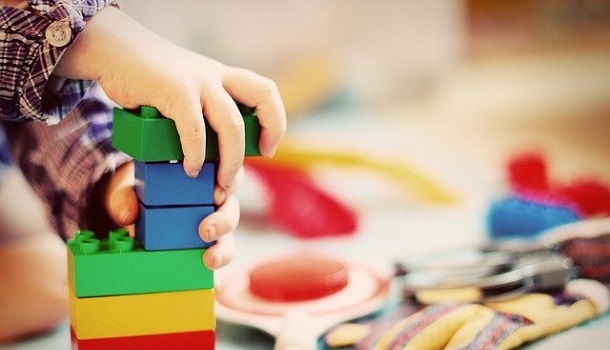 Betreuung - Das Bild zeigt Kinderhände, die mit Bausteinen spielen und im Hintergrund mehr Spielzeug